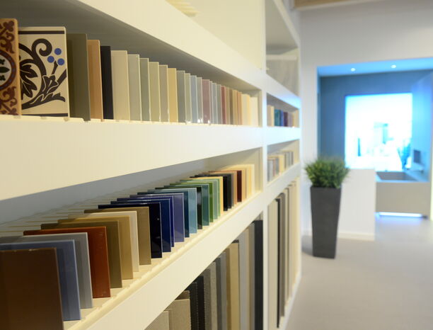 Mehrere Fliesen in verschiedenen Farben und mit verschiedenen Dekoren in einem Regal.